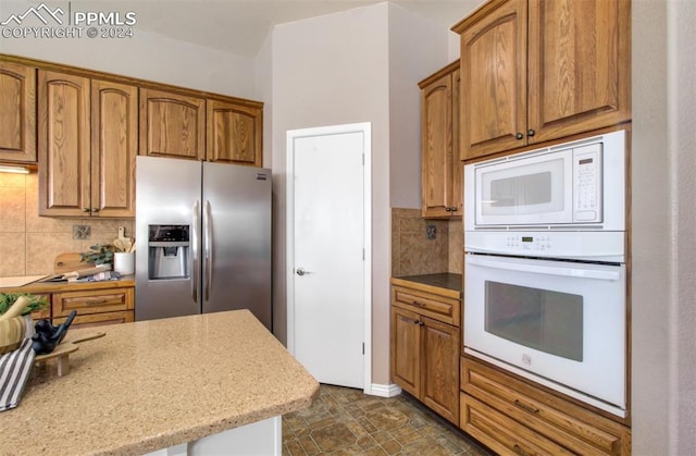 kitchen with tasteful backsplash, light stone countertops, and white appliances