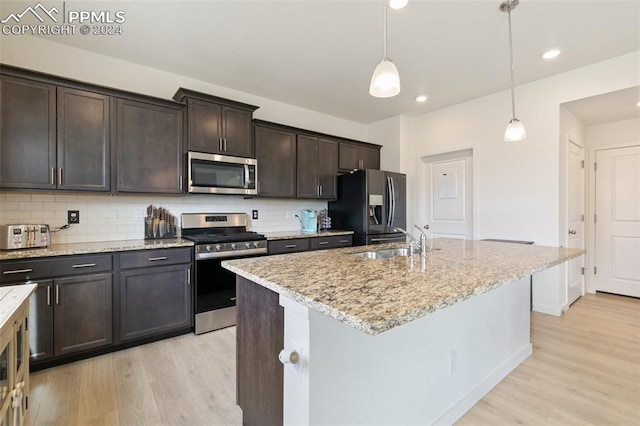 kitchen featuring a kitchen island with sink, sink, pendant lighting, light hardwood / wood-style floors, and stainless steel appliances