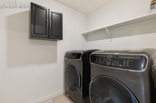 laundry area featuring light tile patterned flooring, washer and dryer, and cabinets