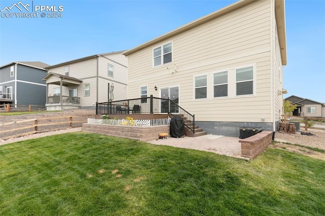 rear view of house with a patio, a lawn, and a wooden deck