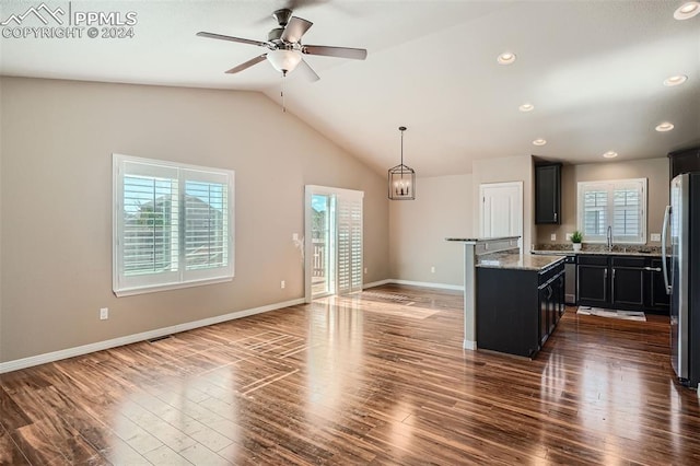 kitchen with lofted ceiling, dark wood-type flooring, light stone countertops, and a healthy amount of sunlight