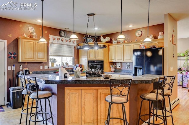 kitchen with light brown cabinetry, black appliances, light hardwood / wood-style flooring, a center island, and hanging light fixtures