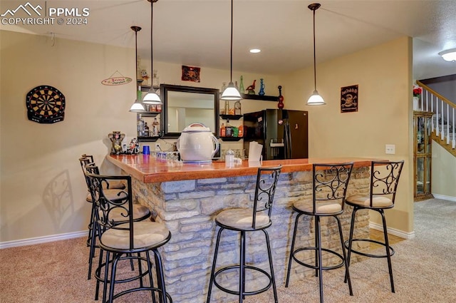 bar featuring black fridge with ice dispenser, light colored carpet, and hanging light fixtures