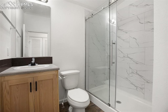 bathroom with vanity, a shower with shower door, and toilet