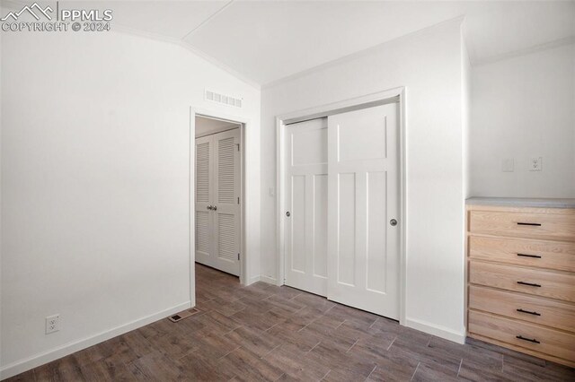 unfurnished bedroom featuring a closet, dark wood-type flooring, and lofted ceiling