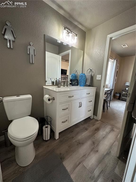 bathroom featuring vanity, a textured ceiling, toilet, and wood-type flooring