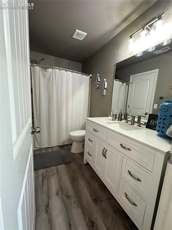 bathroom featuring toilet, a shower with curtain, hardwood / wood-style floors, vanity, and a textured ceiling