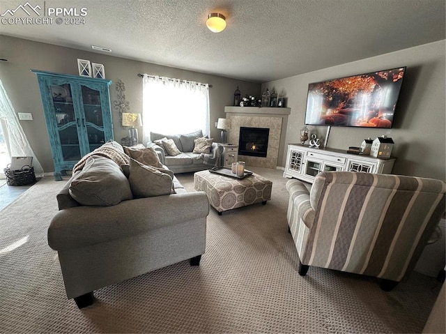 living room featuring a tiled fireplace, a textured ceiling, and carpet floors