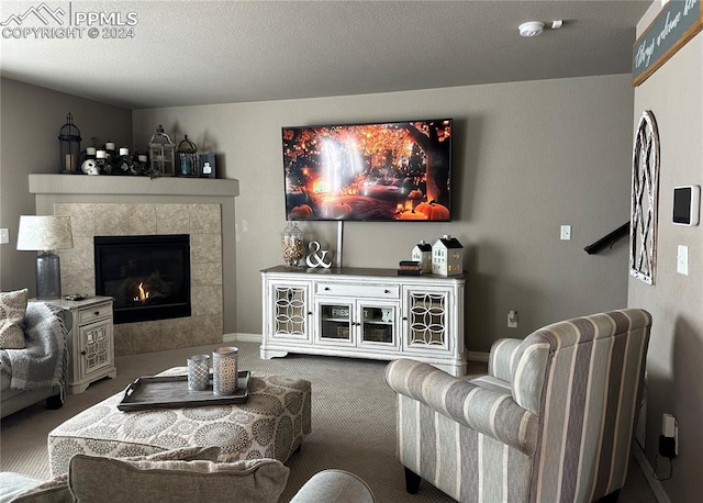 carpeted living room featuring a textured ceiling and a tile fireplace