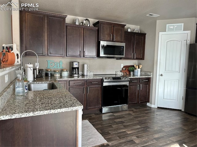 kitchen with dark hardwood / wood-style floors, light stone countertops, dark brown cabinetry, appliances with stainless steel finishes, and a textured ceiling