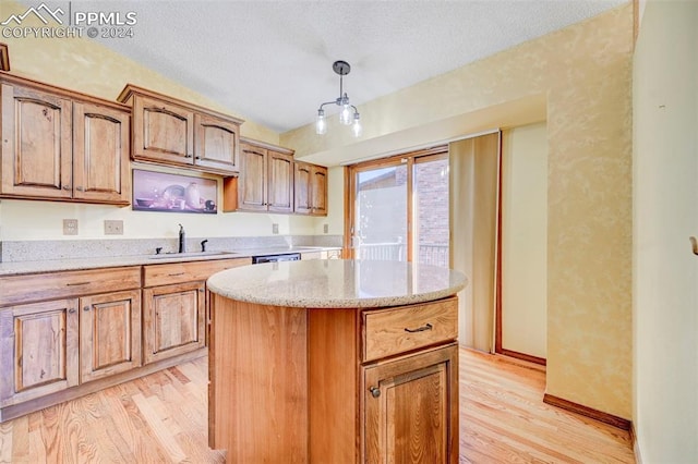 kitchen with sink, a center island, decorative light fixtures, light wood-type flooring, and a textured ceiling