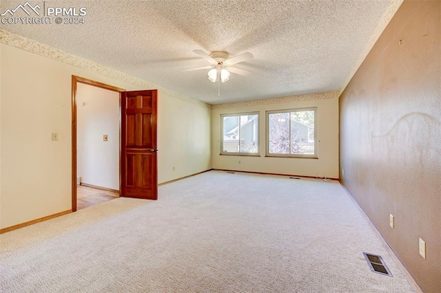 unfurnished room with ceiling fan, a textured ceiling, and light colored carpet