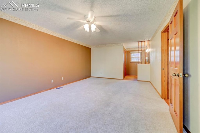 spare room featuring light carpet, a textured ceiling, and ceiling fan