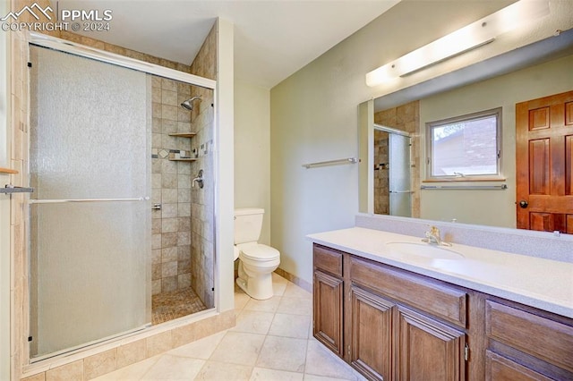 bathroom featuring toilet, a shower with shower door, vanity, and tile patterned floors