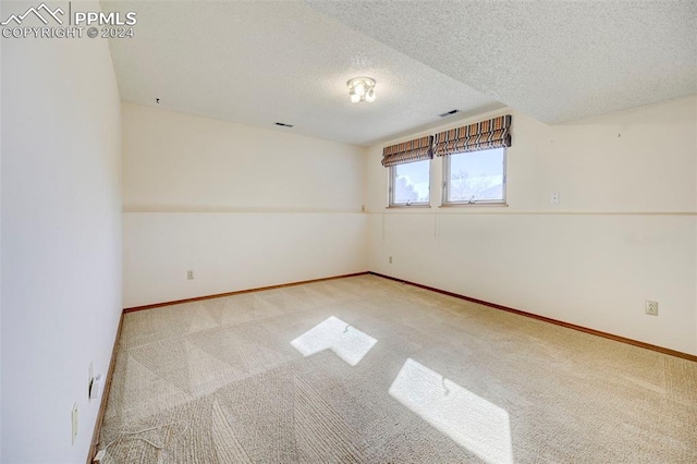 empty room featuring a textured ceiling and light colored carpet