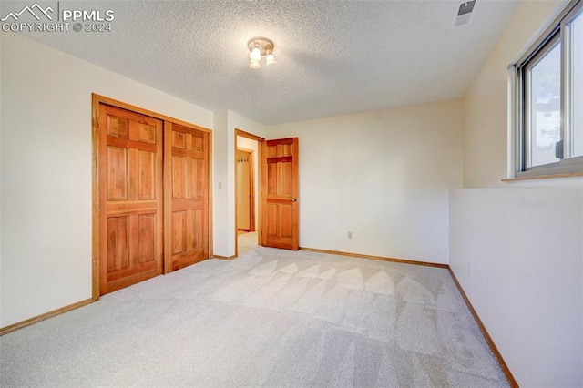 unfurnished bedroom with a closet, light carpet, and a textured ceiling