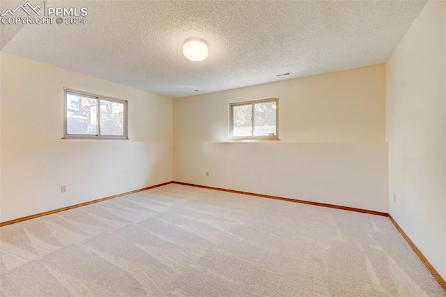 spare room with light carpet and a textured ceiling