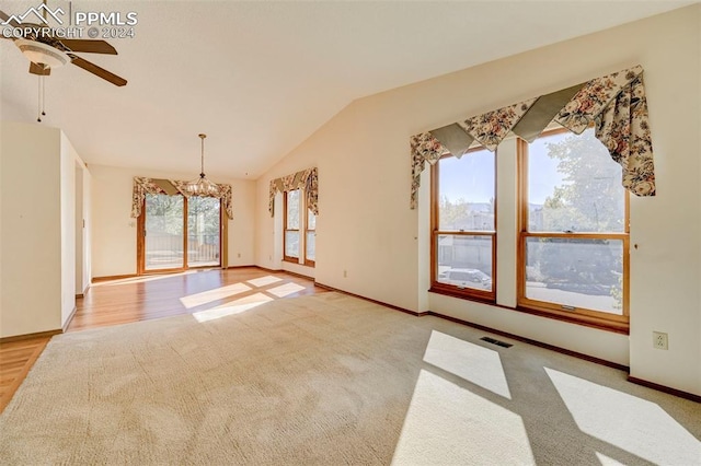 unfurnished room with light hardwood / wood-style floors, ceiling fan with notable chandelier, and vaulted ceiling