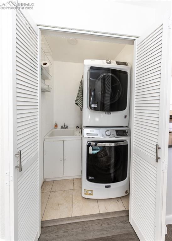 laundry area with stacked washer / dryer and wood-type flooring