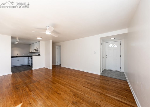 unfurnished living room featuring sink, wood-type flooring, and ceiling fan