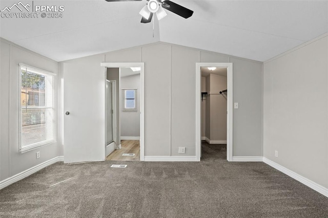 unfurnished bedroom featuring lofted ceiling, carpet floors, a spacious closet, and ceiling fan