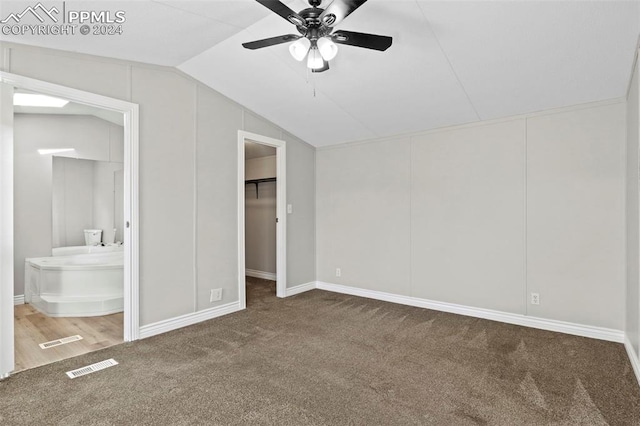 unfurnished bedroom featuring lofted ceiling, carpet, ceiling fan, a spacious closet, and ensuite bath