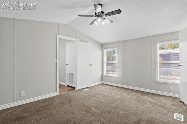 unfurnished bedroom with multiple windows, carpet flooring, lofted ceiling, and ceiling fan