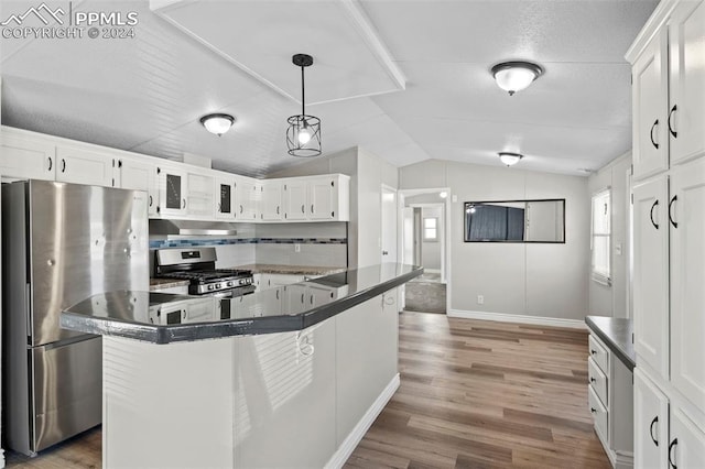 kitchen featuring appliances with stainless steel finishes, vaulted ceiling, white cabinets, and hardwood / wood-style flooring