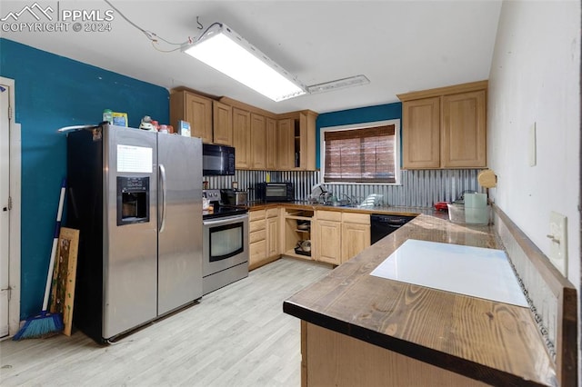 kitchen featuring black appliances, light hardwood / wood-style flooring, kitchen peninsula, and decorative backsplash