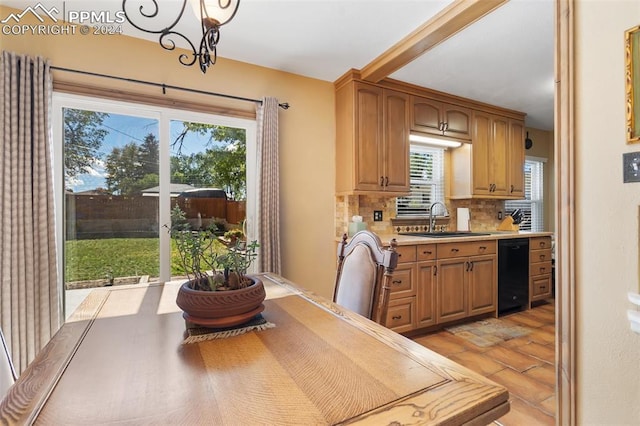 kitchen featuring sink, an inviting chandelier, black dishwasher, backsplash, and decorative light fixtures