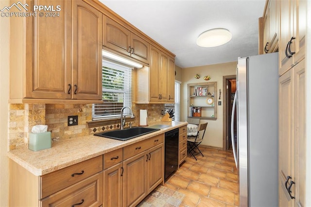 kitchen with backsplash, sink, stainless steel fridge, light stone countertops, and black dishwasher