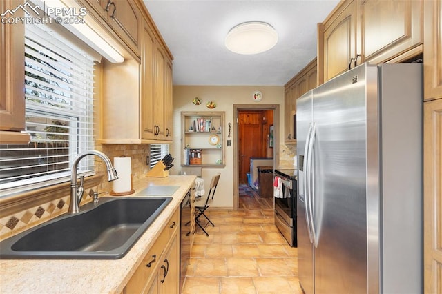 kitchen with backsplash, light brown cabinets, sink, and stainless steel appliances