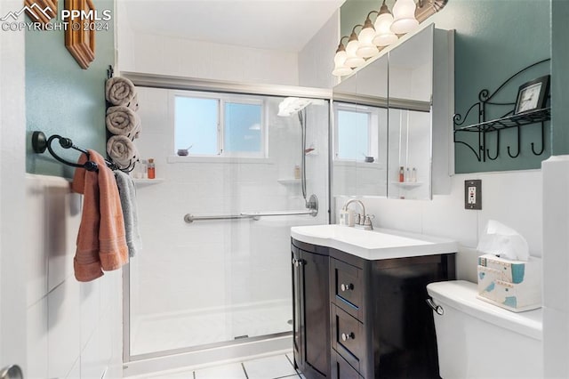 bathroom featuring tile patterned flooring, vanity, a shower with shower door, and toilet