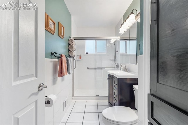 bathroom featuring toilet, vanity, tile patterned floors, and a shower with door