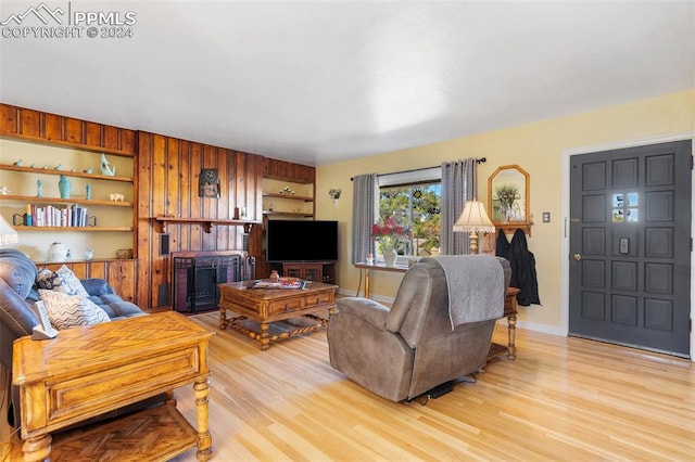 living room with light hardwood / wood-style flooring and wood walls