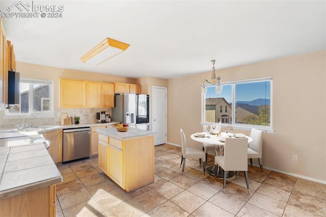 kitchen featuring a center island, stainless steel appliances, hanging light fixtures, and plenty of natural light