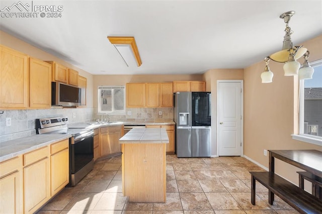 kitchen with tasteful backsplash, light brown cabinetry, a kitchen island, stainless steel appliances, and tile counters