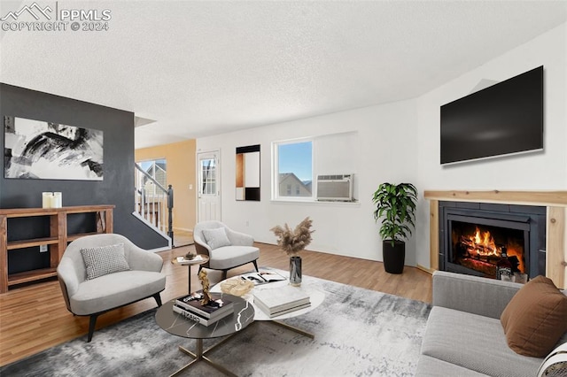 living room with an AC wall unit, a textured ceiling, and hardwood / wood-style floors