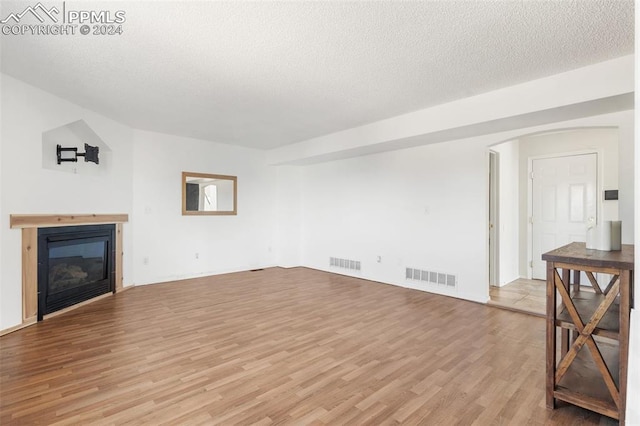 unfurnished living room featuring a textured ceiling and light wood-type flooring