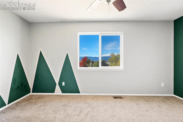 carpeted spare room with ceiling fan and a textured ceiling