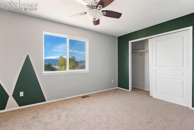 unfurnished bedroom featuring a textured ceiling, carpet floors, a closet, and ceiling fan