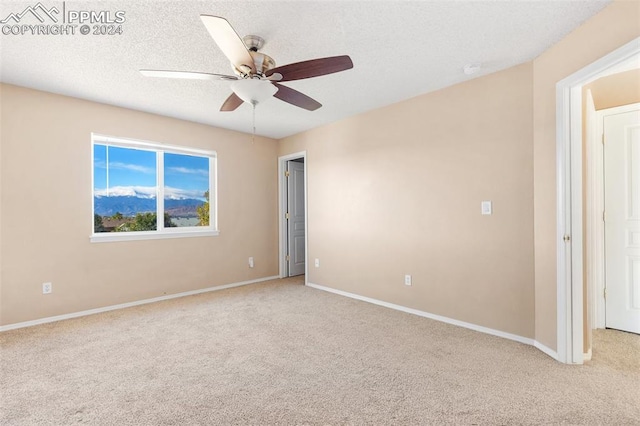 unfurnished room featuring light carpet, a textured ceiling, and ceiling fan