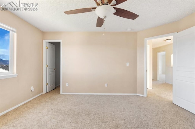 empty room featuring light carpet, a textured ceiling, and ceiling fan