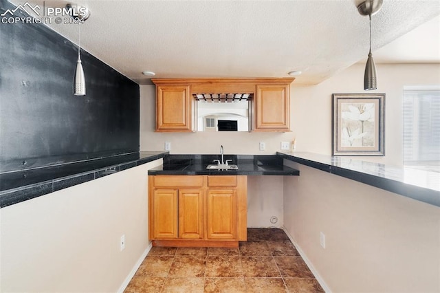 kitchen featuring sink, decorative light fixtures, and a textured ceiling