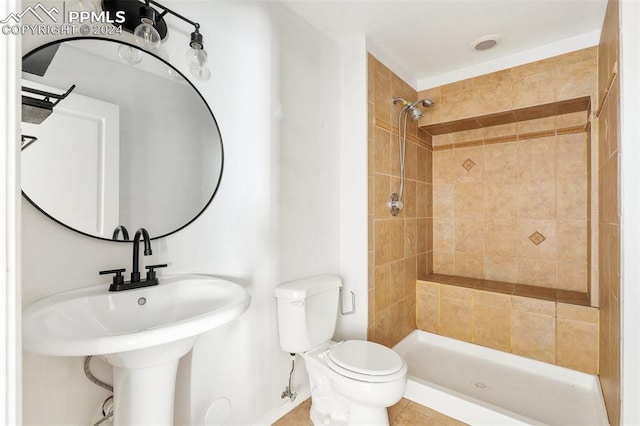 bathroom with tiled shower, toilet, and tile patterned flooring