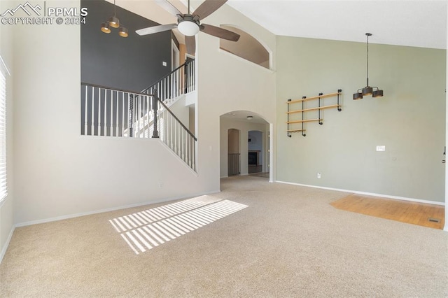 unfurnished living room featuring ceiling fan, high vaulted ceiling, and carpet flooring