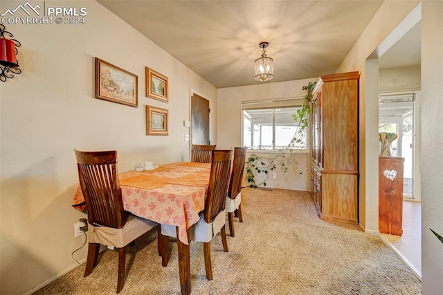 dining space featuring light colored carpet and an inviting chandelier