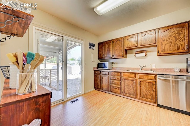 kitchen with appliances with stainless steel finishes, sink, and light hardwood / wood-style floors