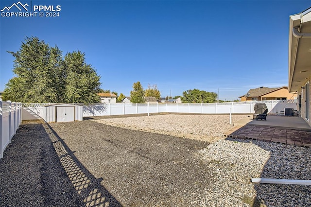 view of yard with a patio, a storage shed, and central air condition unit