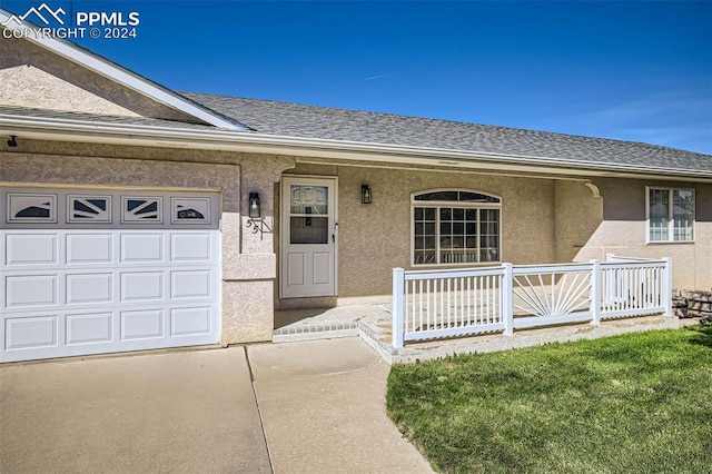 doorway to property featuring a yard, covered porch, and a garage